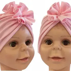 Uroczy, różowy turban dla noworodka z ozdobnym kwiatkiem na czubku głowy.
