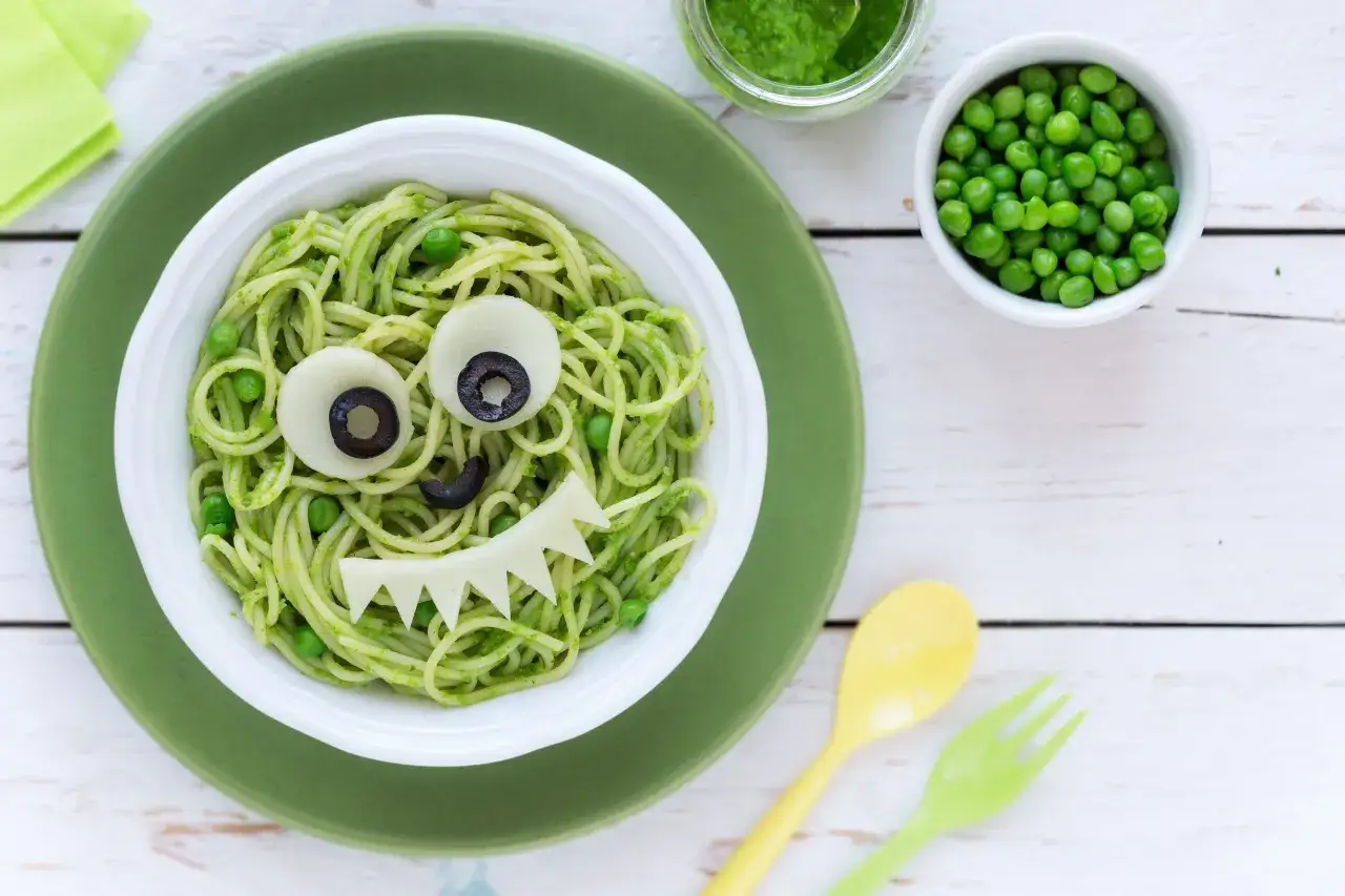 Kolacja dla 3 latka: spaghetti z pesto, groszkiem i uśmiechniętym potworkiem z sera i oliwek.