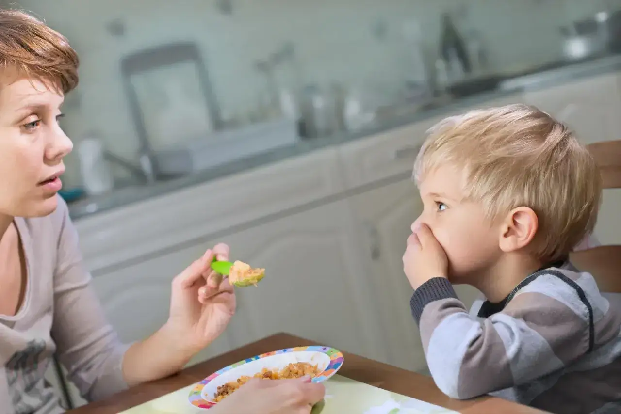Mama próbuje nakarmić niejadka. Jak zwiększyć apetyt u dziecka? Może kolorowa łyżeczka pomoże?